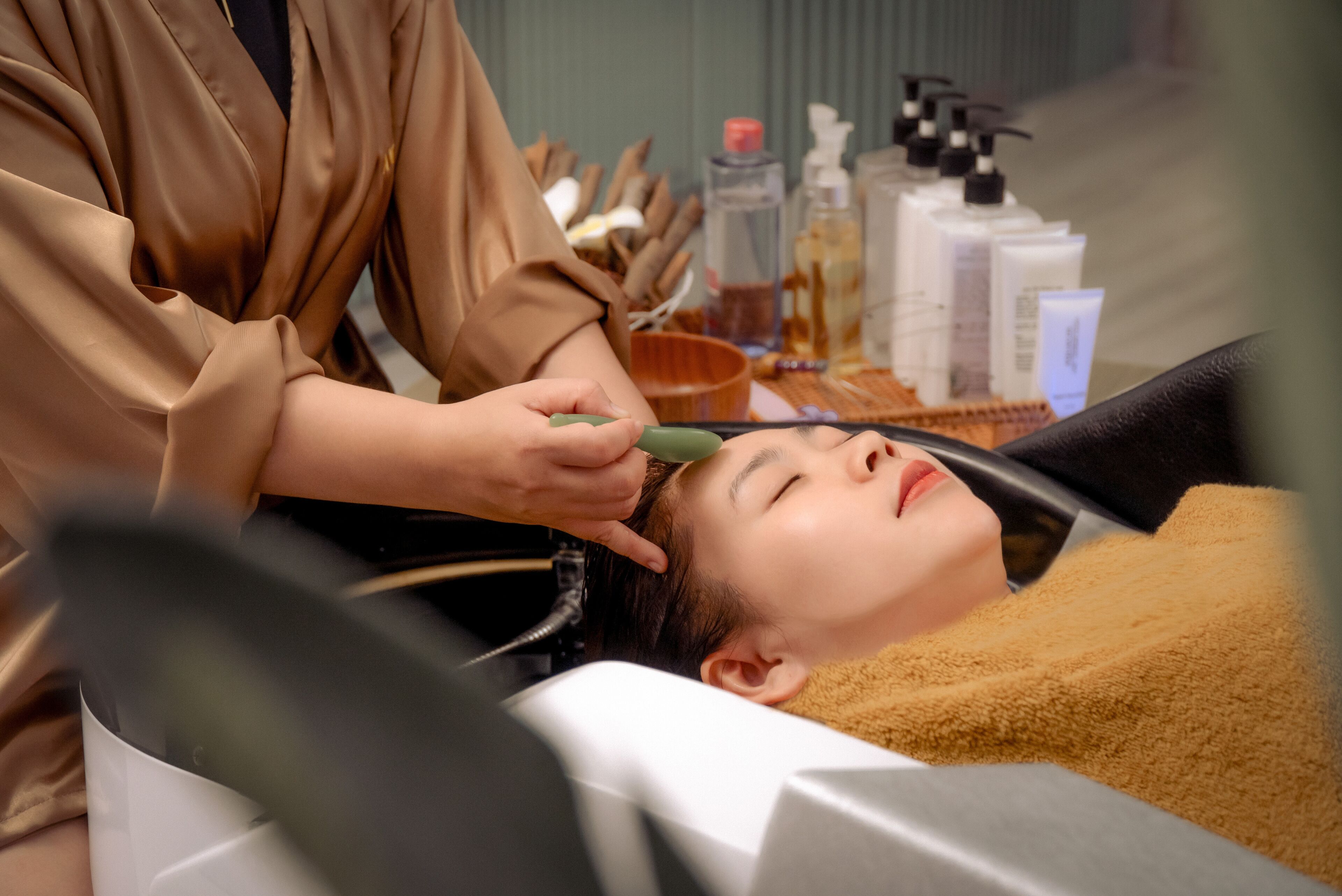 A person receiving a facial treatment with various skincare products on a table.
