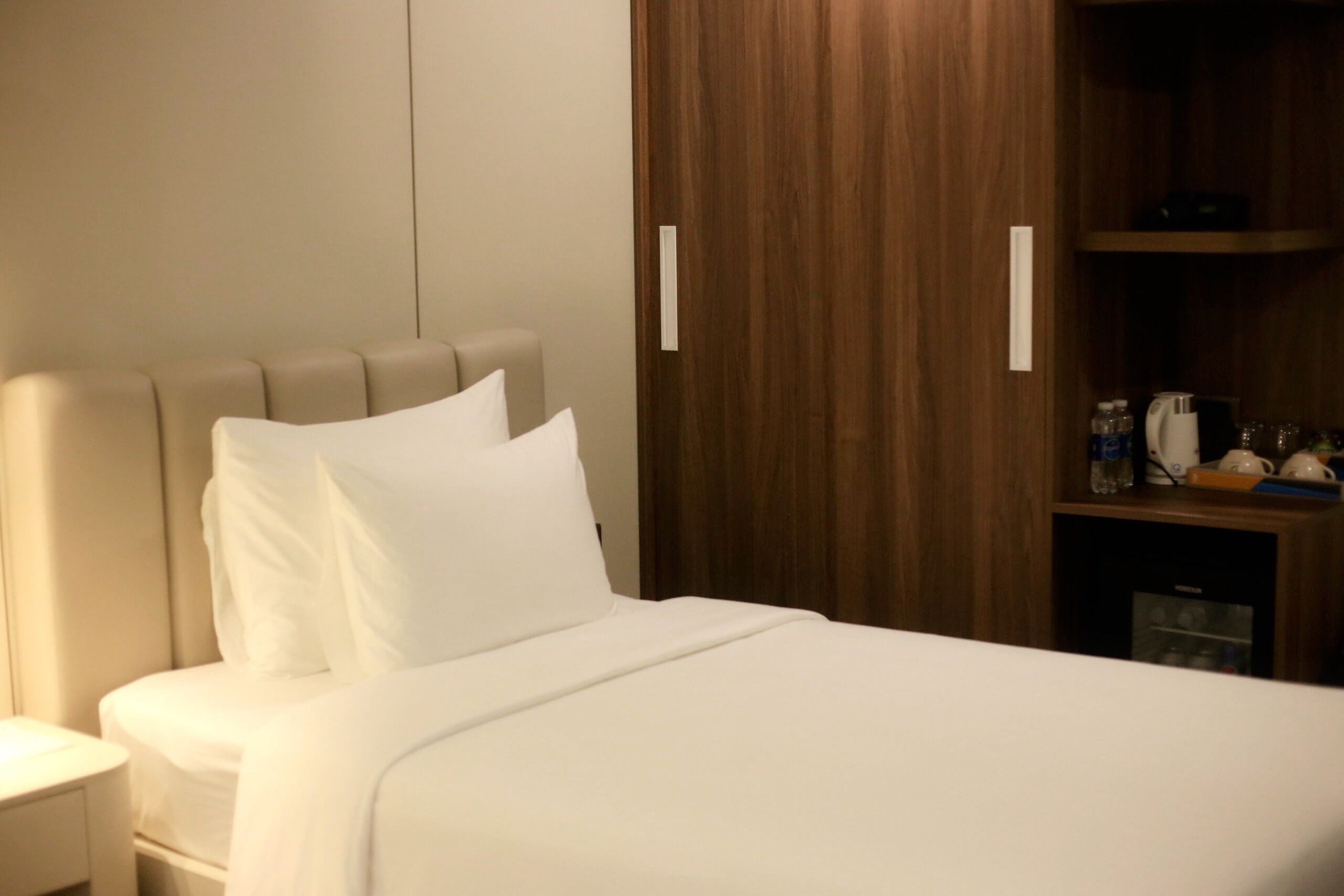 Ein ordentlich bezogenes Bett mit weißen Leinen in einem Hotelzimmer.