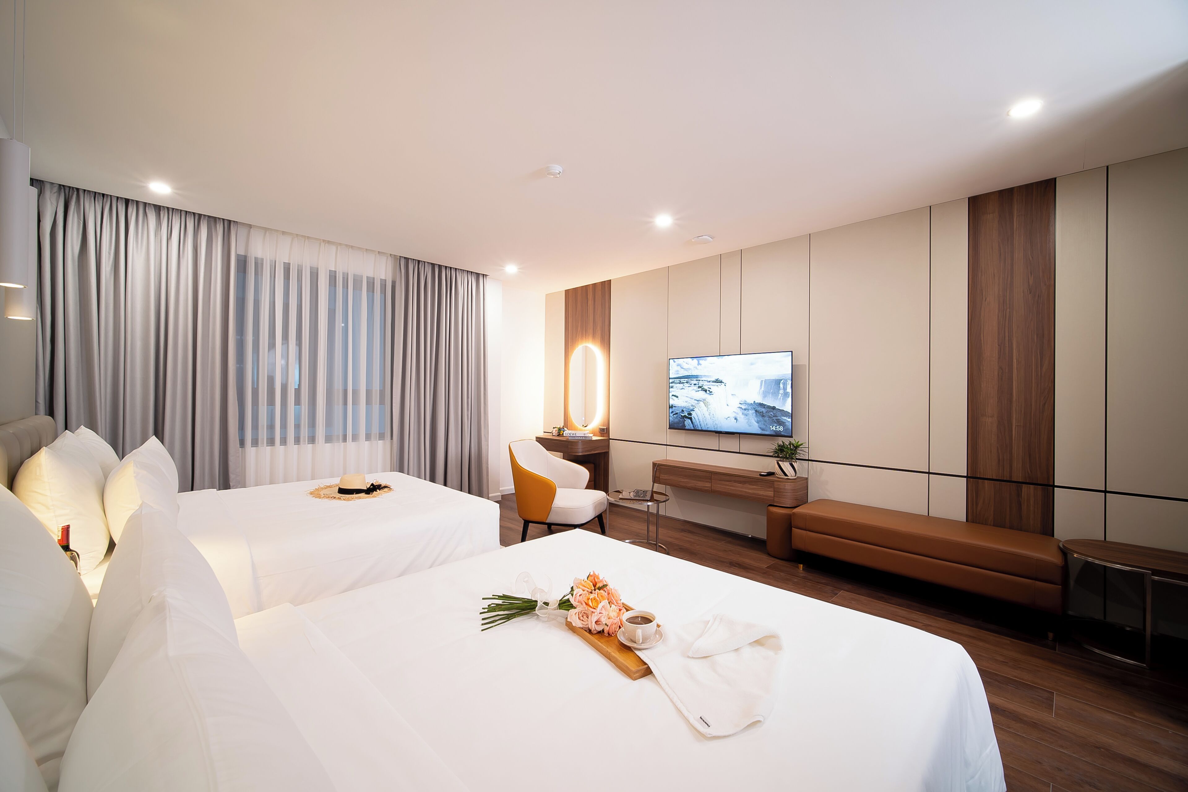 A hotel room with two beds, a TV, a desk, and a seating area.