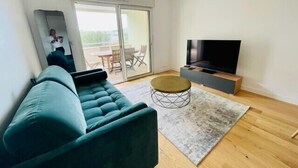 Een moderne woonkamer met een bank, een televisie en een schuifdeur naar een terras.