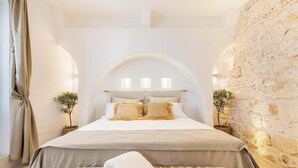 Ein Schlafzimmer mit einem großen Bett, einer hölzernen Bank und einer Steinwand.