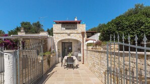 A stone building with a tiled patio, a gate, and a small table with chairs. - Affaccio Calipso - PT by BarbarHouse (Marittima)