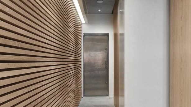 A modern hallway with a wooden slatted wall, a concrete floor, and a metallic elevator door. - Luxury Urban Oasis: with Garden and Private Studio (London)