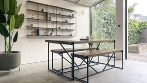 A modern interior with a concrete floor, a metal-framed table, and a white wall with shelves. - Luxury Urban Oasis: with Garden and Private Studio (London)
