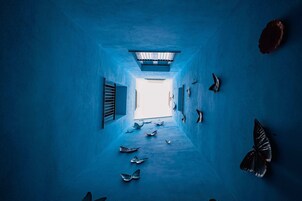 Un couloir aux murs et au plafond bleus, qui mène à une sortie lumineuse.