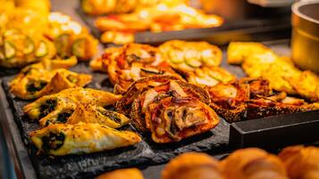 Diversos produtos de panificação em uma bandeja, incluindo doces e pão.