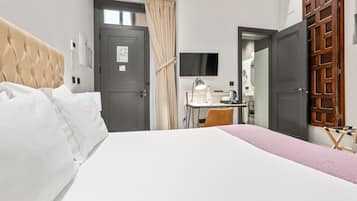 A hotel room with a bed, a desk, a chair, a TV, and a wardrobe.
