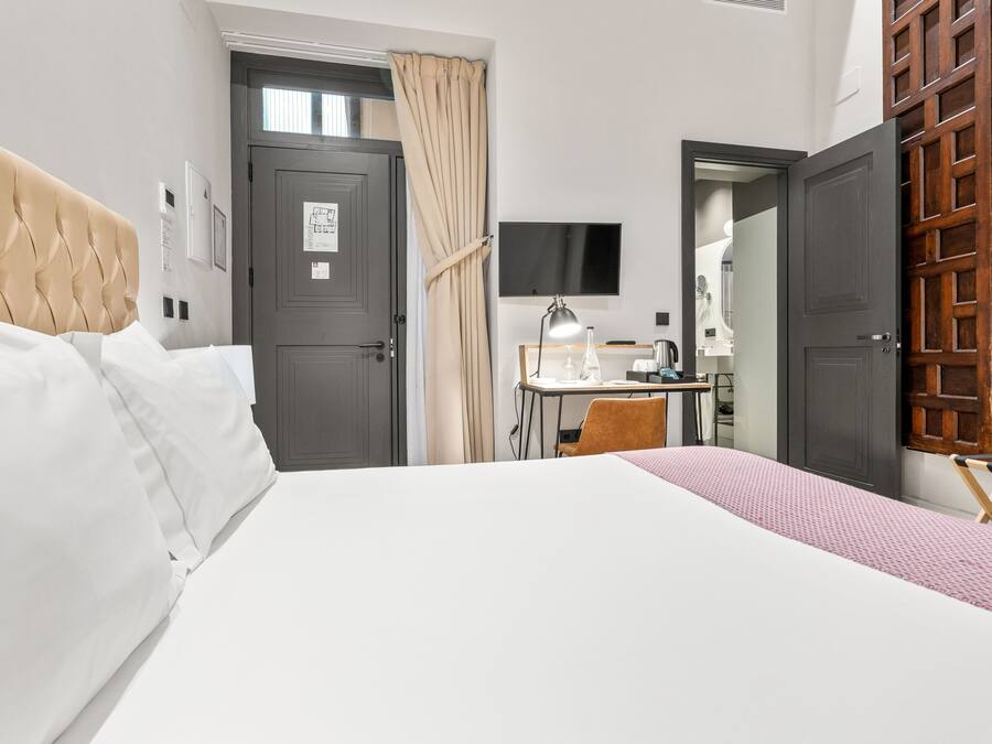 A hotel room with a bed, a desk, a chair, a TV, and a wardrobe.
