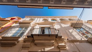 A building facade with classical architectural elements, including columns, a central pediment, and multiple windows with shutters. - Casa Alhaja by Shiadu (Seville)