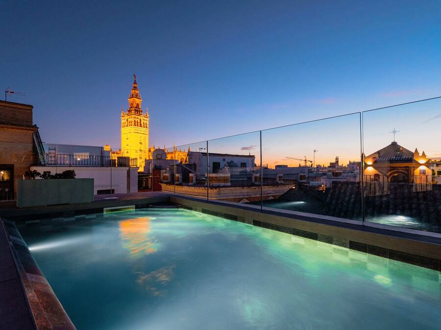 Ein Pool auf dem Dach mit Blick auf einen historischen Turm und ein traditionelles Gebäude.