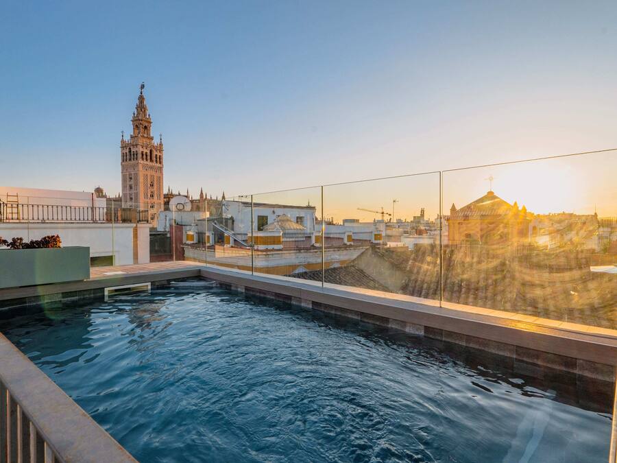 Piscina no terraço com vista para uma torre histórica e edifícios modernos.