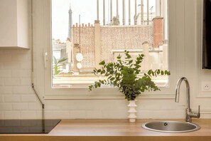 Uma cozinha com janela, pia e um vaso com planta.
