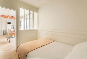Quarto com cama, janela e vista para uma cozinha.