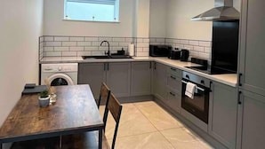 A modern kitchen with grey cabinets, a built-in oven, and a window above the sink. - Remarkable 1-bed Studio in Downham Market (Downham Market)