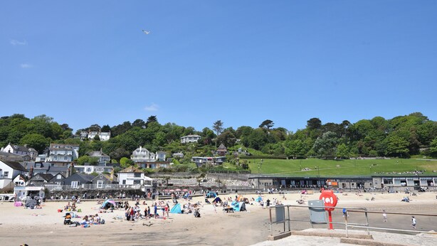 A beach with people, tents, and houses in the background. - Fawley (Lyme Regis)