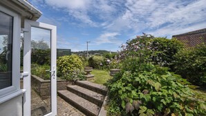 A garden with steps leading to a door, surrounded by greenery and flowering plants. - Fawley (Lyme Regis)
