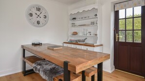 A kitchen with a wooden table, a clock, and shelves with kitchenware. - Fawley (Lyme Regis)