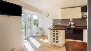 A modern kitchen with a large window, a built-in wine cooler, and a coffee machine. - Fawley (Lyme Regis)