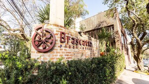 A brick wall with the sign "Brascata Pizza Grill" and a large pizza wheel logo. - Casa na Lapa com Piscina e Churrasqueira (São Paulo)
