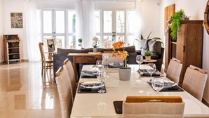 A dining area with a table set for four, surrounded by cushioned chairs, a wooden cabinet, and a potted plant. - Casa na Lapa com Piscina e Churrasqueira (São Paulo)