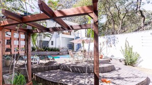 A wooden pergola with a swing set, a pool, and outdoor seating. - Casa na Lapa com Piscina e Churrasqueira (São Paulo)
