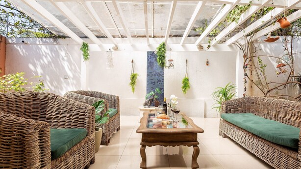 A sunlit room with wicker furniture, a glass coffee table, and hanging plants. - Casa na Lapa com Piscina e Churrasqueira (São Paulo)