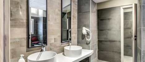 Une salle de bain moderne avec deux vasques rondes blanches, un grand miroir et une douche à l’italienne.