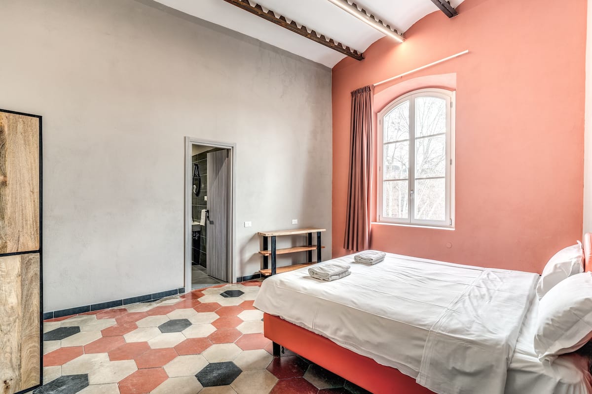 Um quarto com uma cama, uma janela e uma porta.