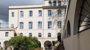 A multi-story building with arched windows and a central courtyard with potted plants. - Borgo Ripa Urban Travel (Rome)
