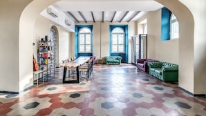 A spacious room with a large table, chairs, a green sofa, and a bookshelf. - Borgo Ripa Urban Travel (Rome)