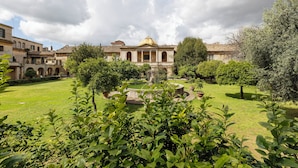 A courtyard with a fountain, surrounded by greenery and historic buildings with classical architecture. - Borgo Ripa Urban Travel (Rome)