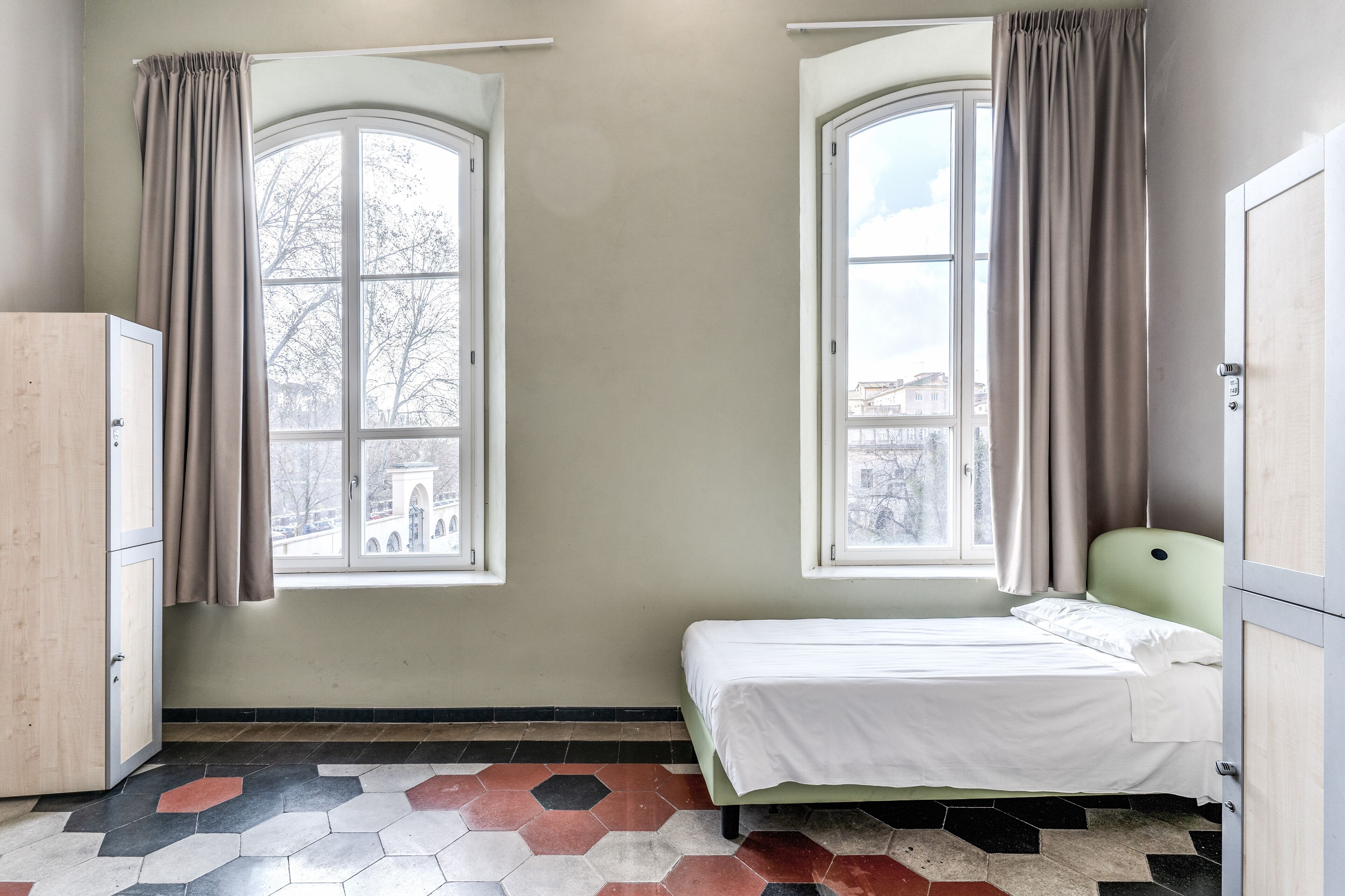 Una habitación con dos ventanas, una cama y un armario.