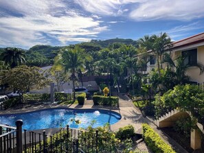 Une piscine entourée d’une végétation luxuriante, avec un paysage vallonné en arrière-plan.