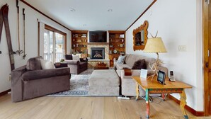 Un salon chaleureux avec une cheminée, des étagères en bois et un canapé.