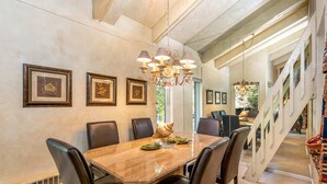 A dining area with a marble table, black leather chairs, and a chandelier.