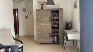 A modern living room with a sofa, a dining table, a bookshelf, and a lamp. - Casa Típica Canaria (Playa Honda)
