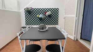 A dining area with a black table and white chairs, a decorative wall with a lattice pattern, and a potted plant on the wall. - Casa Típica Canaria (Playa Honda)