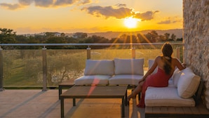 Un balcón con sofá y mesa, con vistas a un paisaje pintoresco al atardecer.