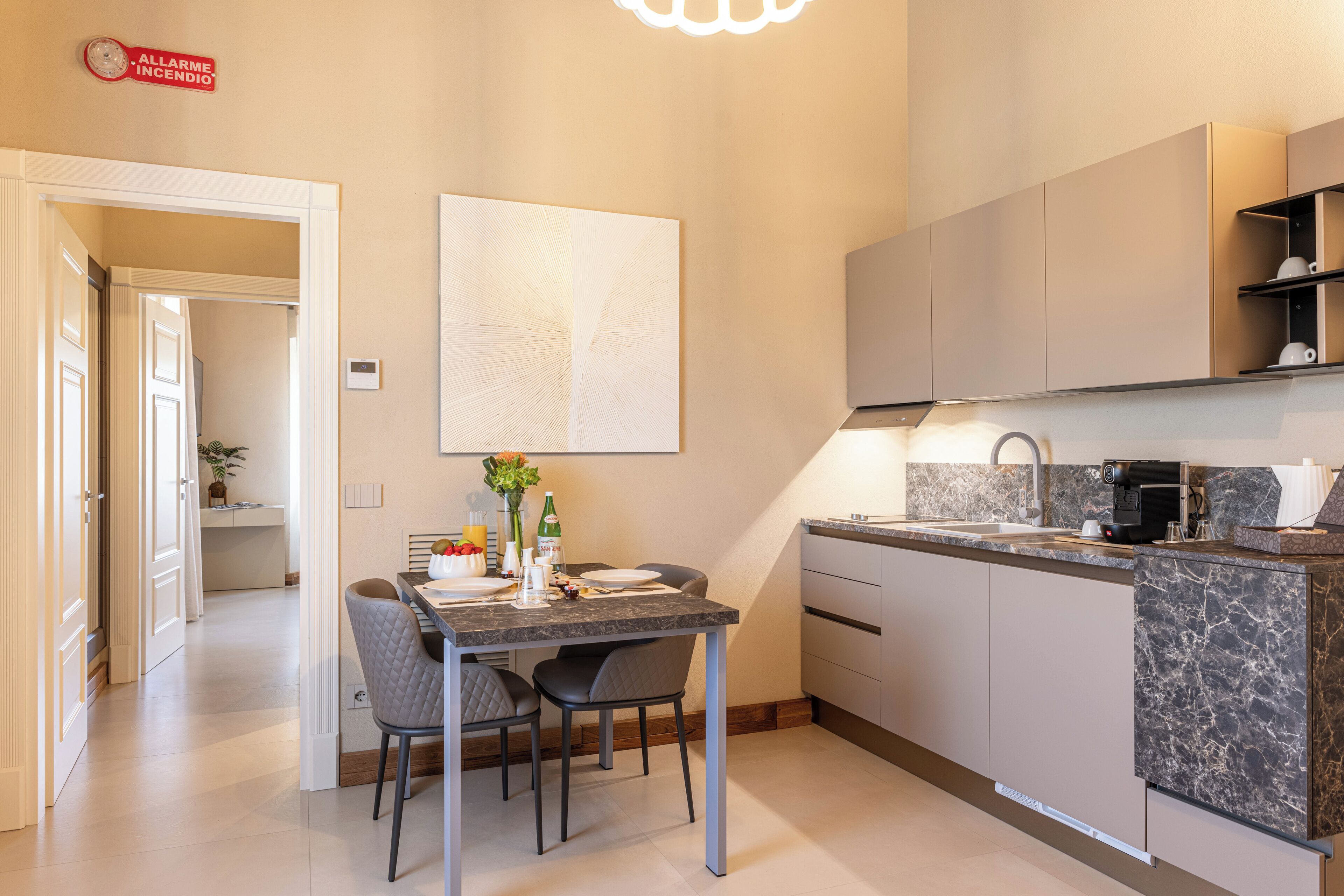A modern kitchen with a marble countertop, built-in cabinets, and a dining area with two chairs.