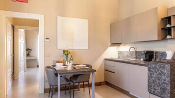 A modern kitchen with a marble countertop, built-in cabinets, and a dining area with two chairs.