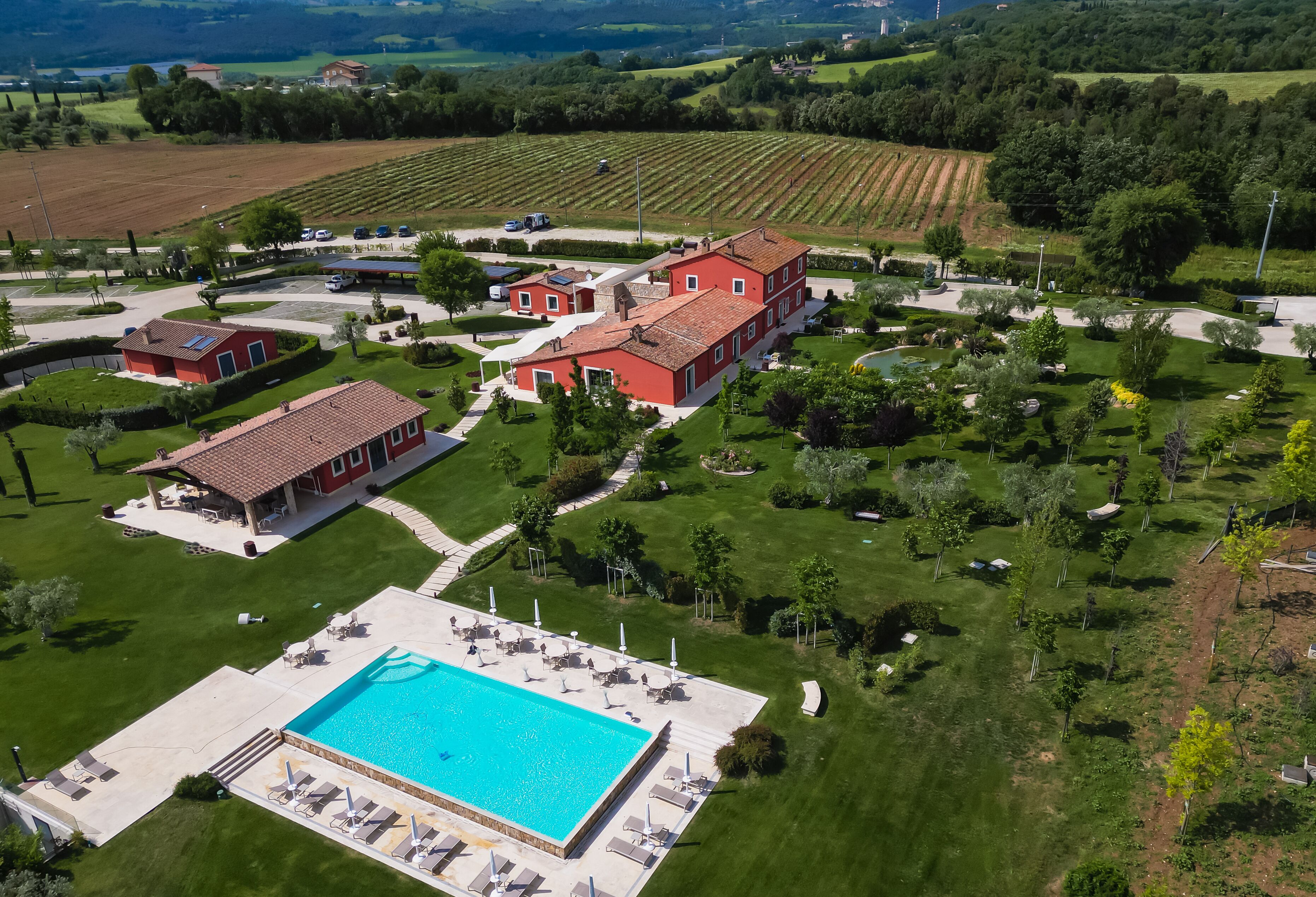 A large property with a swimming pool, multiple buildings, and surrounding green fields.