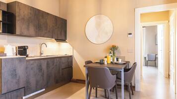A modern kitchen with dark cabinetry, a dining table with chairs, and a round wall art piece.