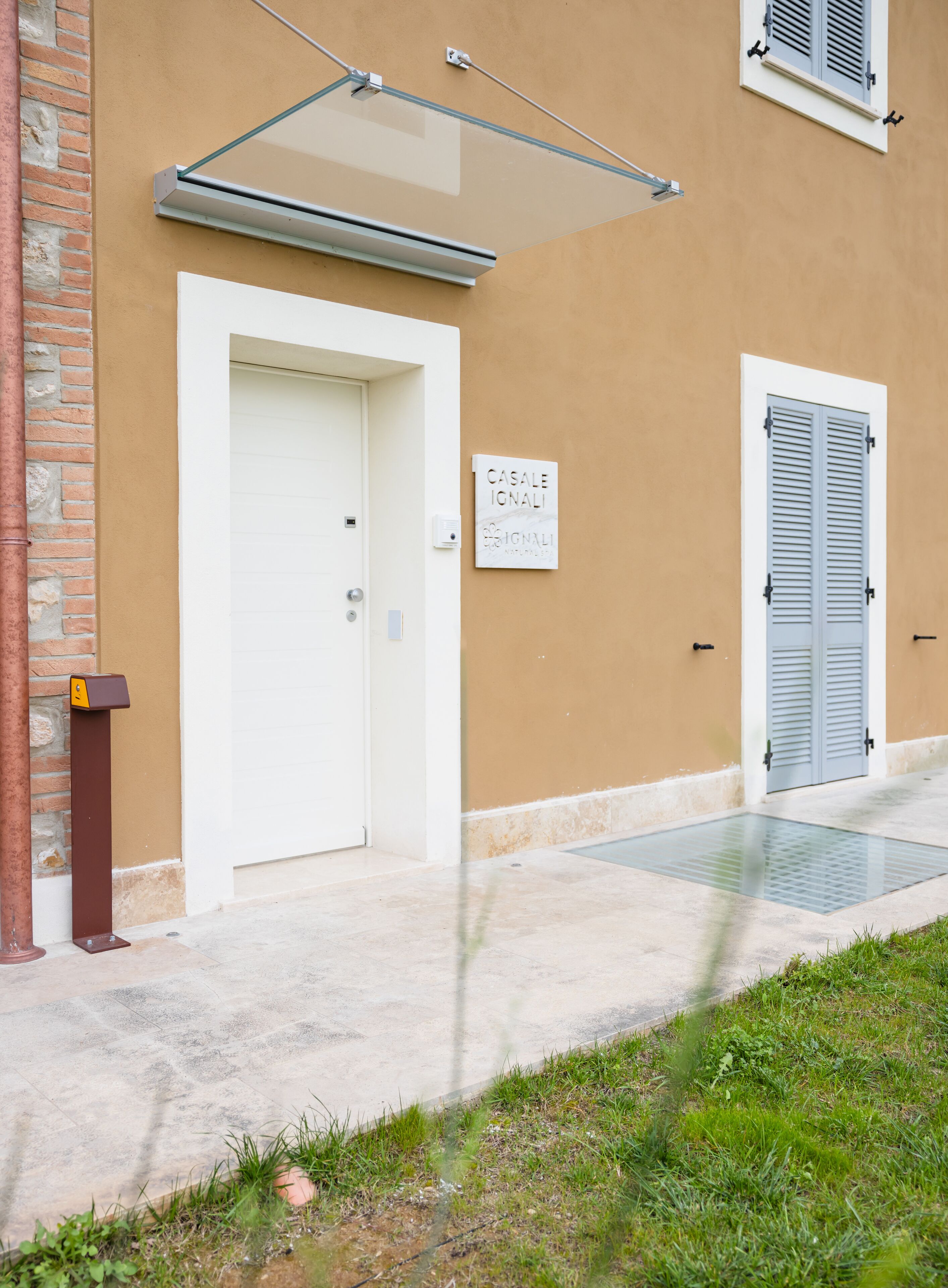 A building entrance with a white door, a mailbox, and a sign reading "CASALE IONALI".