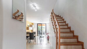 A modern interior with a wooden staircase, a dining area, and a view through a glass door. - GO2TENERIFE Apart’Vera Duplex Santiago 2 (Costa Adeje)