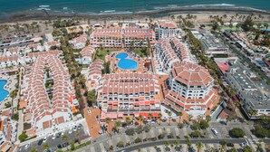 An aerial view of a resort with multiple buildings, a central pool, and a beach in the background. - GO2TENERIFE Apart’Vera Duplex Santiago 2 (Costa Adeje)