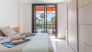 A modern hotel room with a large bed, a balcony with a view, and a sliding door. - GO2TENERIFE Apart’Vera Duplex Santiago 2 (Costa Adeje)