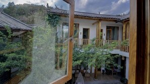 Un edificio tradizionale con un balcone in legno, un giardino e vista sul paesaggio circostante.