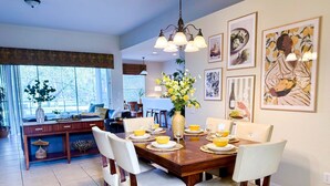 Un comedor con una mesa de madera dispuesta para cuatro, sillas blancas y un jarrón de flores.