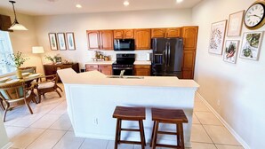 Una cocina moderna con armarios de madera, una isla central y un comedor con sillas y una mesa.