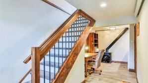 Ein geräumiges Loft mit einer Holztreppe, einem Schreibtisch und einem Kamin.